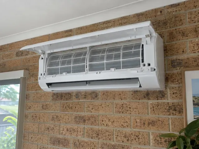 Clean split system with open front panel and visible filters on a brick wall in a home in Worongary